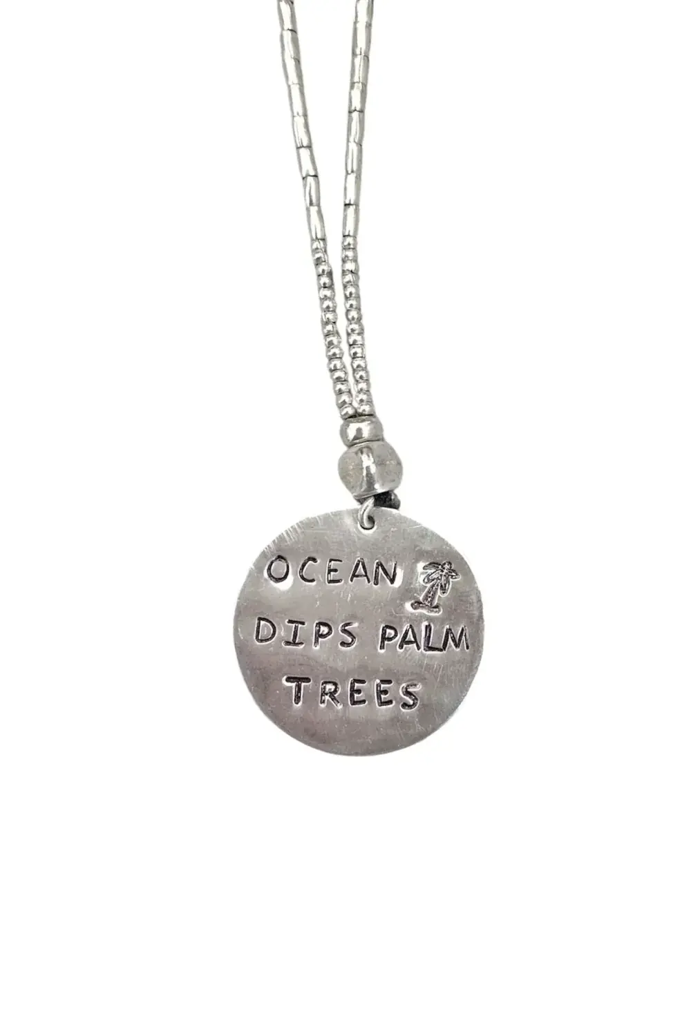 ocean inspired large handmade sterling silver disc pendant on long pure silver chain necklace. 'ocean dips, palms trees' hand stamped onto the silver disc. ocean safe island girl jewellery